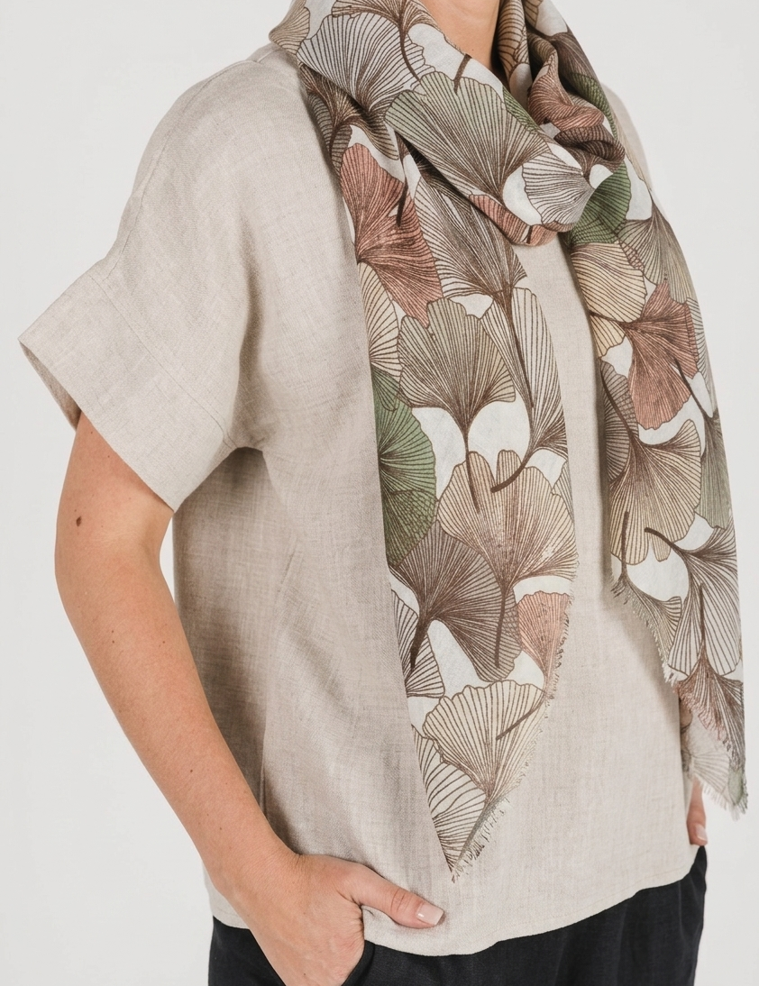 Model wearing an Autumn Gingko Scarf featuring a gingko leaf print in warm autumn hues.