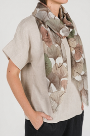 Model wearing an Autumn Gingko Scarf featuring a gingko leaf print in warm autumn hues.